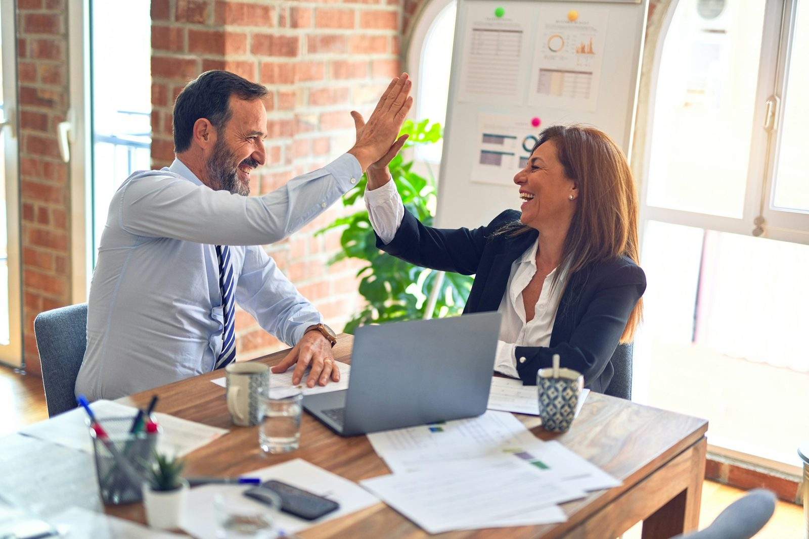 Two advisers shaking hands over a desk